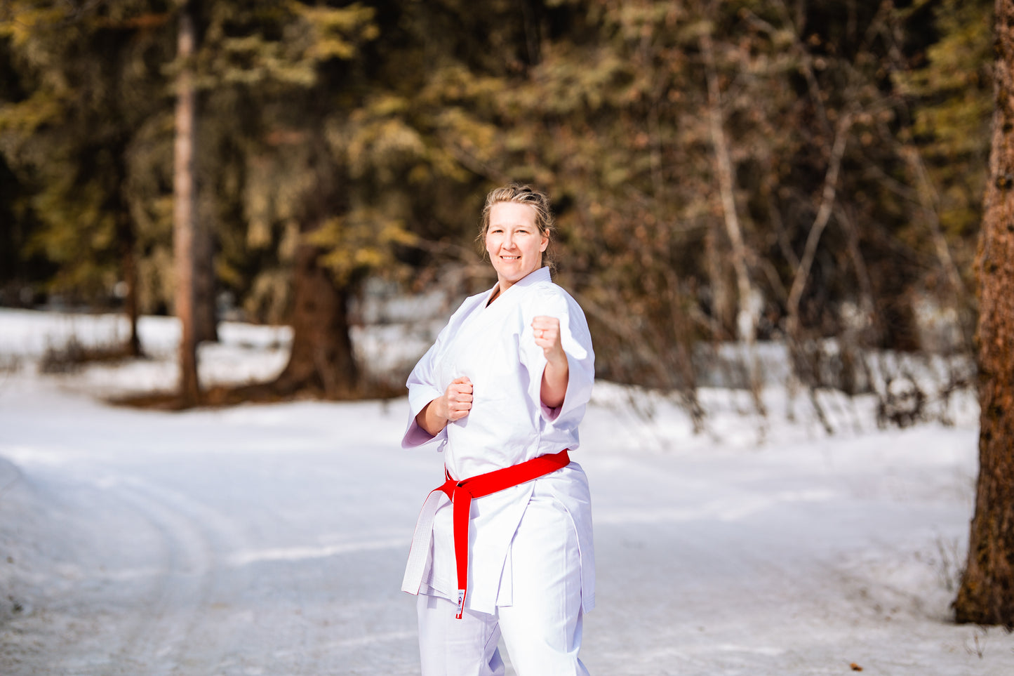 Strong female fighter in white karate gi with red belt
