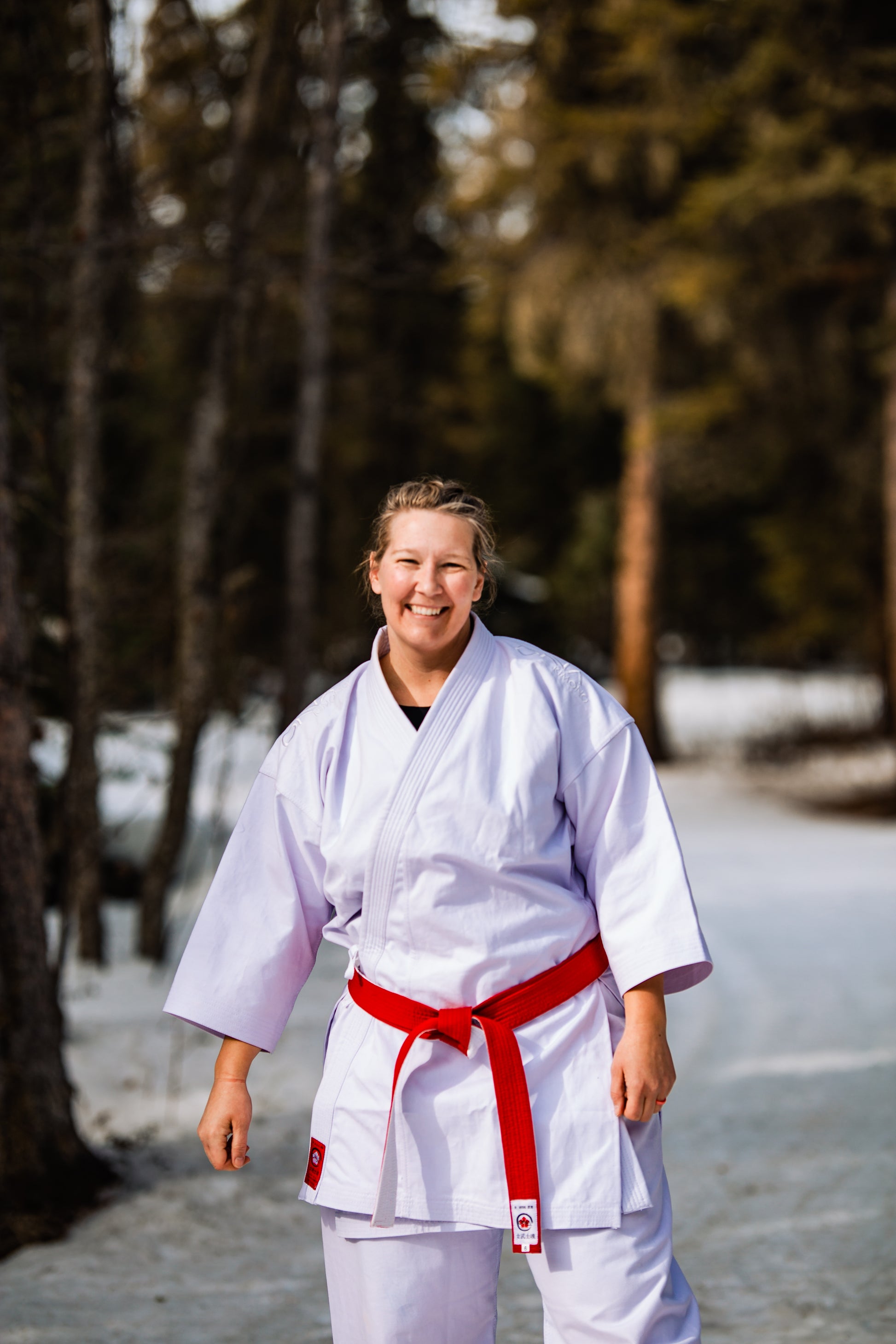 Plus sized woman smiling in karate uniform with red belt