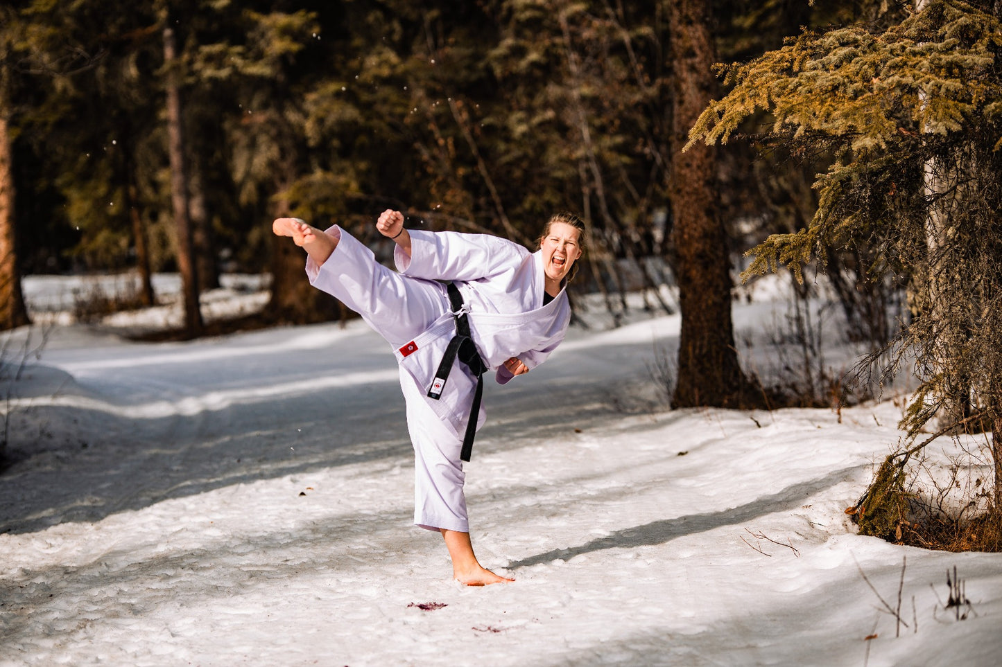 karate blackbelt Woman kicking in the snow 