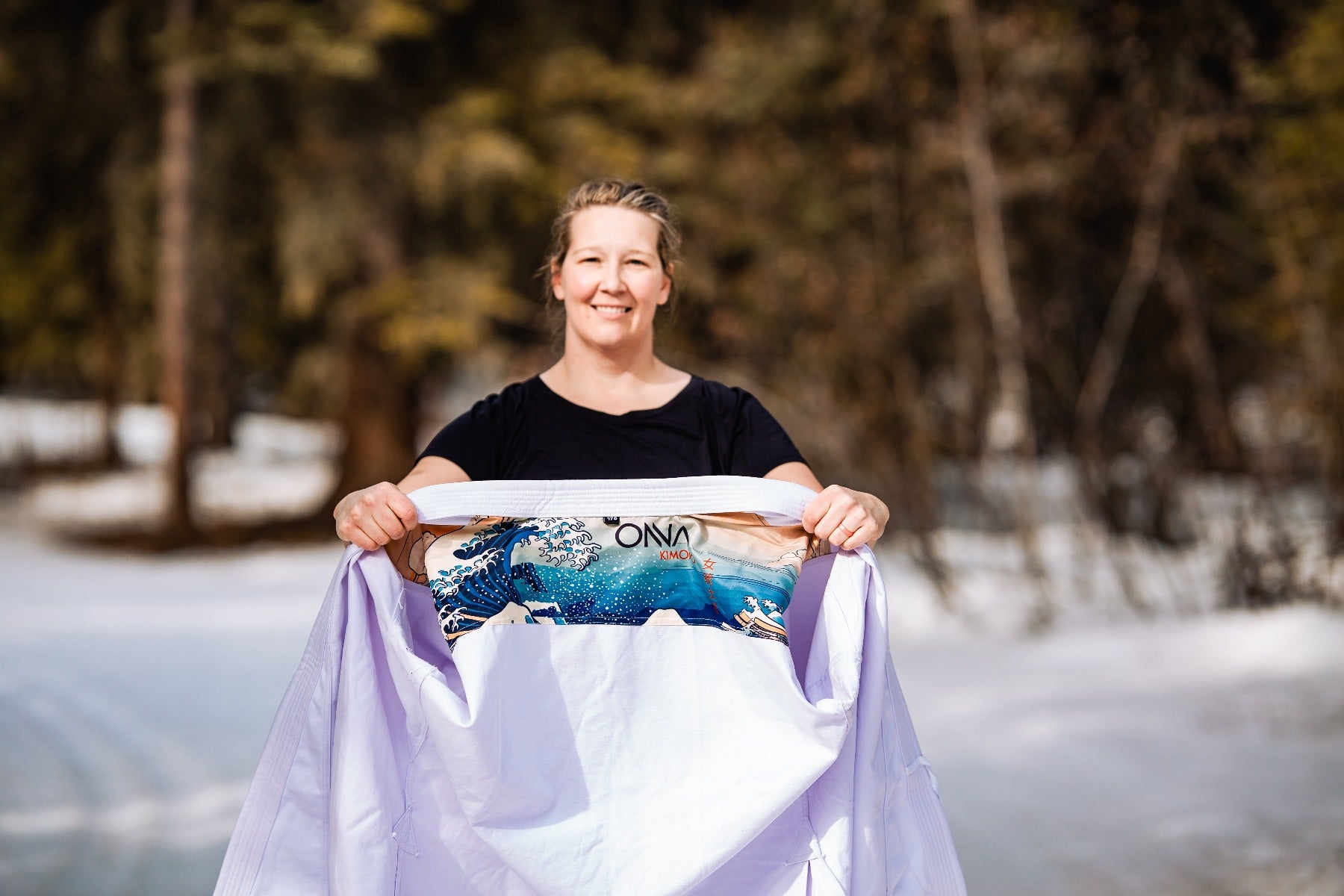 Woman holding karate jacket up and showing an image of wave on inside of karate jacket