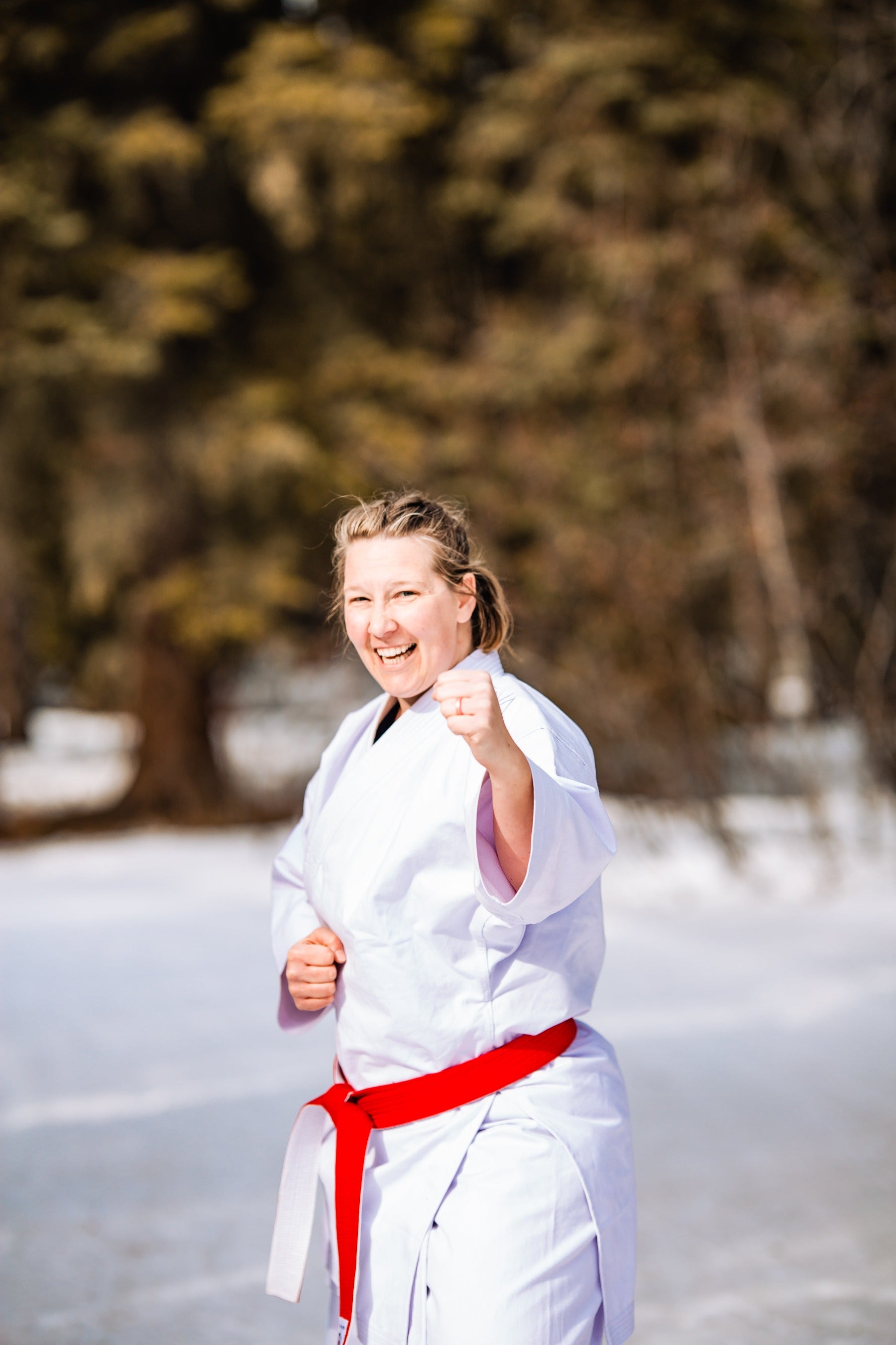 karate woman smiling in the snow with red belt on ready to fight