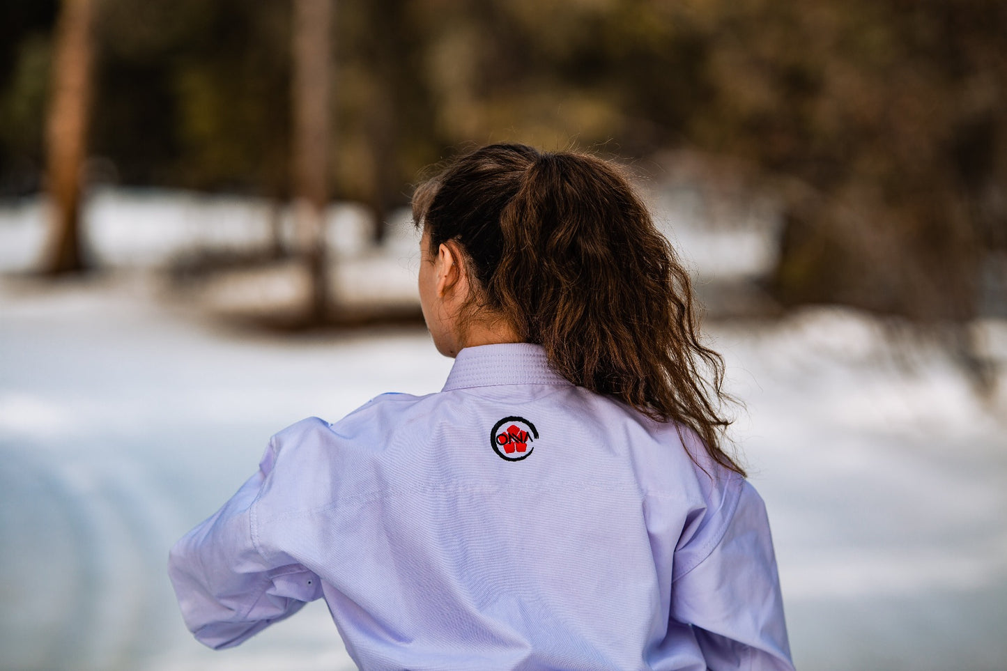 Female karate athlete back of uniform, with red flower embroidery