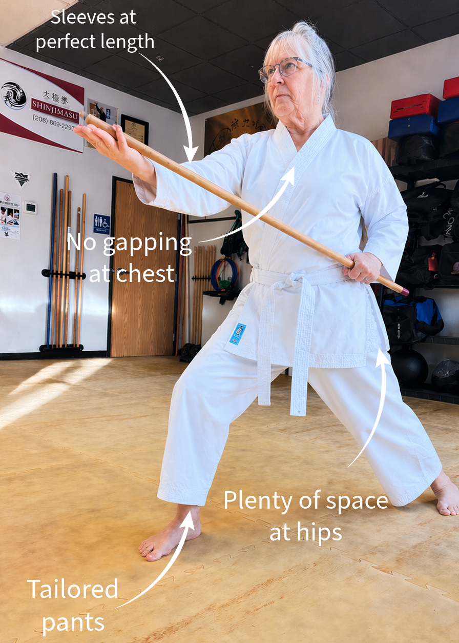 Person in a martial arts uniform demonstrating proper fit with text annotations in a dojo setting.